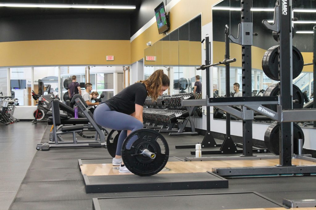 woman in gym about to do a deadlift with a barbell