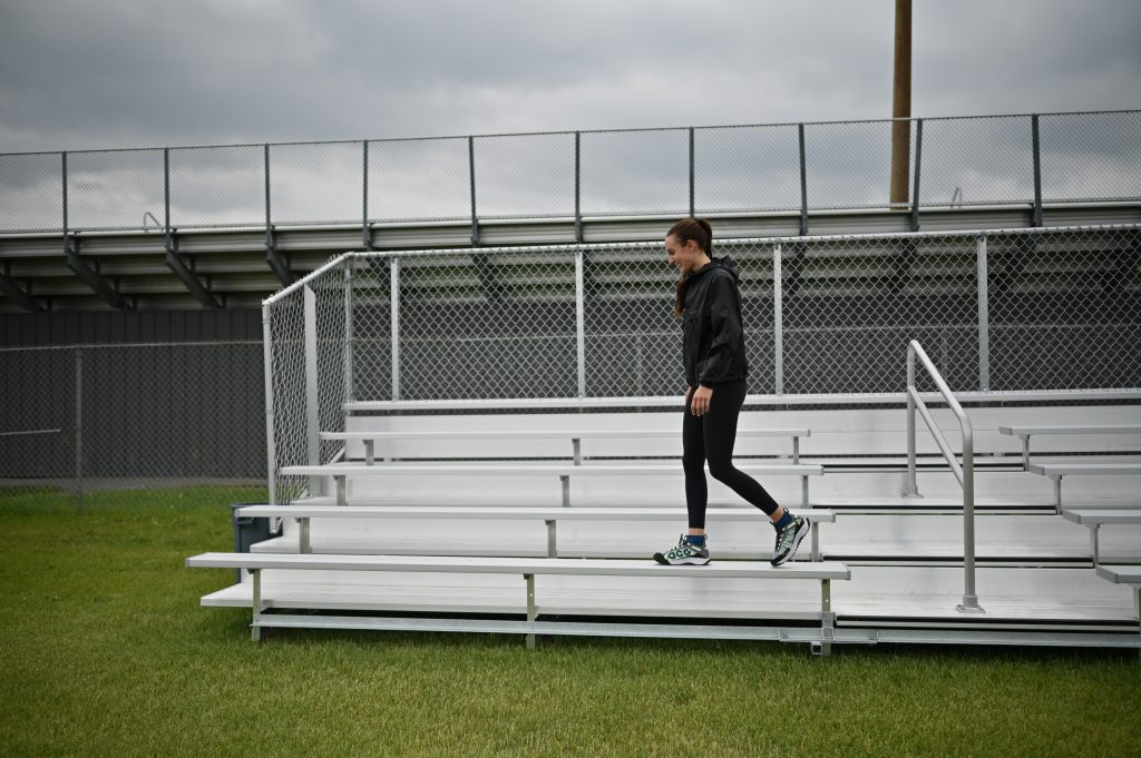 walking along outdoor bleachers, wearing all black