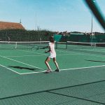 girl playing tennis on the court wearing all white