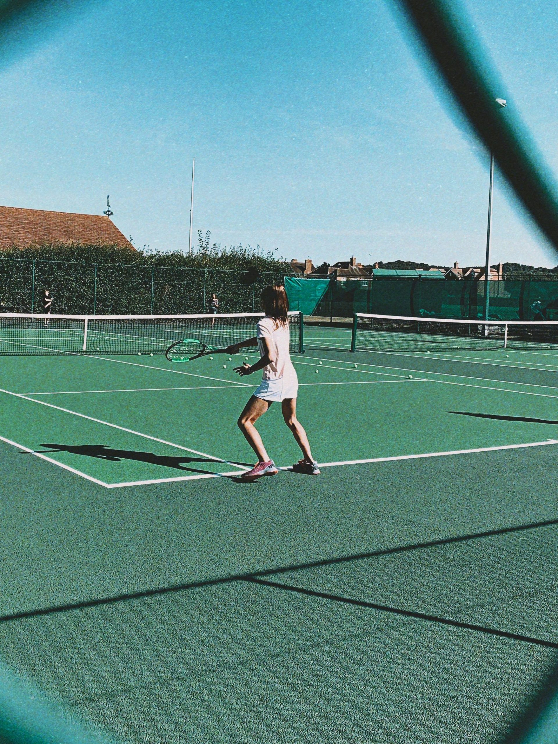 girl playing tennis on the court wearing all white