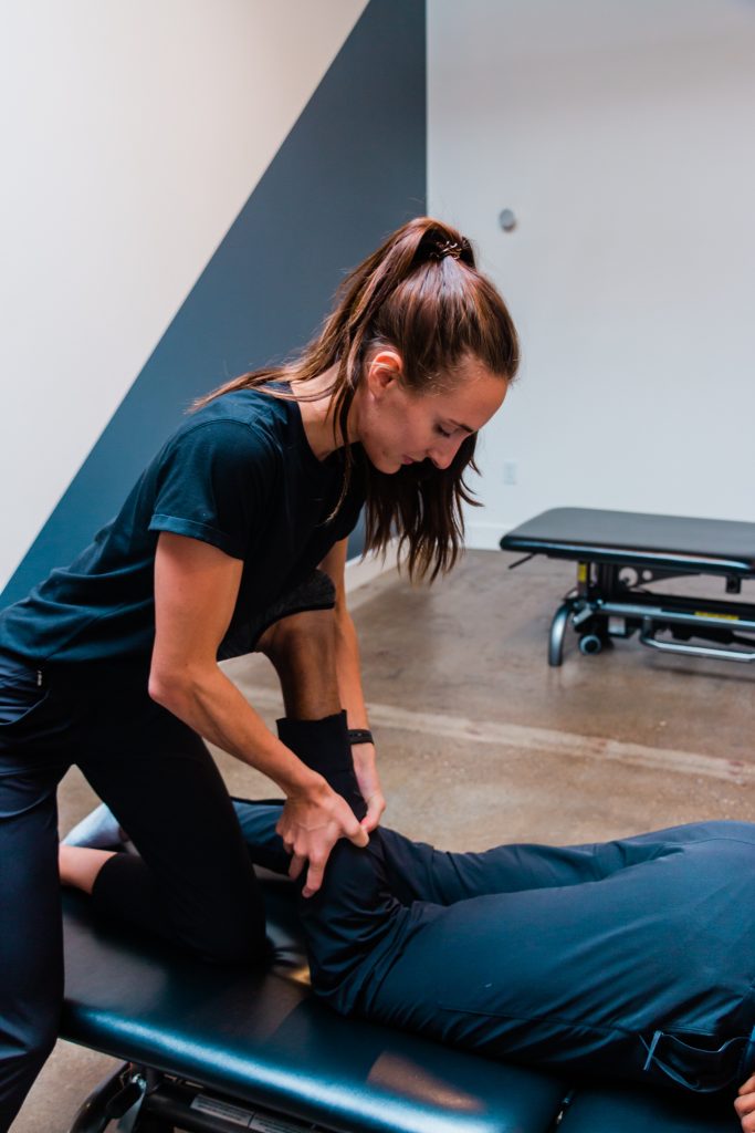 Hannah looking down and treating a patient's calf muscle